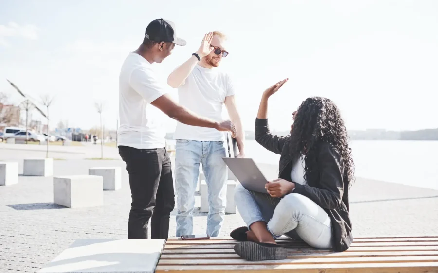Beautiful multi ethnic friends using a laptop in the Street. Youth lifestyle concept